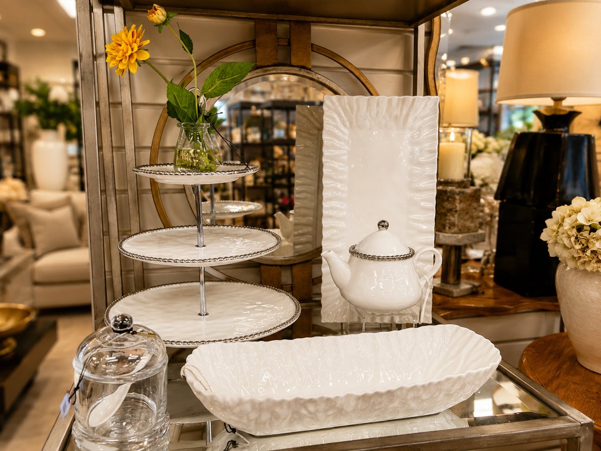 White ceramic tabletop pieces at The Things I Love — a three-tier server with a yellow bloom, rectangular tray, teapot, and oblong serving dish